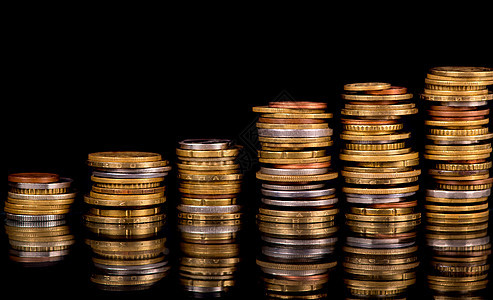 黑背景上的堆叠硬箱金子硬币市场库存宝藏反射金融辅币债务银行背景图片