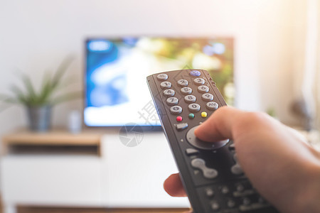 男性手握着电视遥控器 在智能电视上流传客厅监视器视频娱乐渠道程序手指影院溪流按钮图片