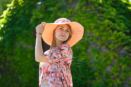 穿着淡夏日服的迷人女孩和佩雷奥帽正在绿色公园行走 享受阳光明媚的暑假成人裙子幸福快乐自由女性帽子微笑晴天公园图片