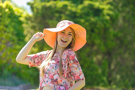 穿着淡夏日服的迷人女孩和佩雷奥帽正在绿色公园行走 享受阳光明媚的暑假花园帽子晴天幸福情感裙子闲暇女士成人喜悦图片