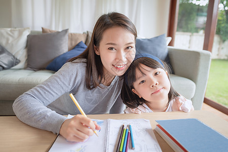 快乐的亚洲母亲教她可爱的小女儿 在家中客厅学学前班 在家起居室学习图片