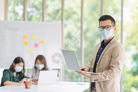 企业雇员在办公室工作时戴面罩 以遵守公司政策 保持卫生技术流感就业职场头脑商务员工消毒剂凝胶面具图片
