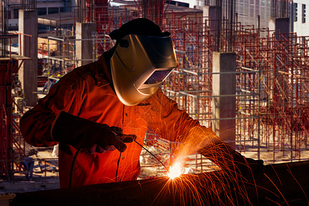 背景为施工现场的基础设施建设项目的工业工人焊接钢结构安全水泥咨询建设者职场工作头盔团队蓝图技术图片