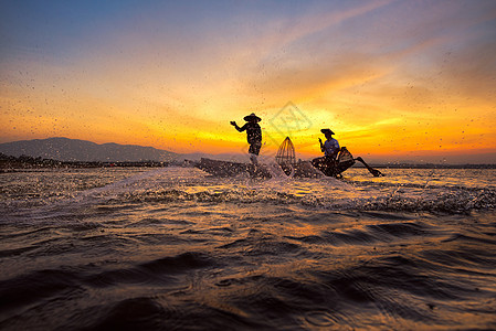 在日出前清晨 木船上的渔民在自然河流上撒网捕捉淡水鱼图片