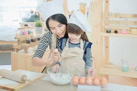 亚裔母亲和女儿正在准备钱 在度假时在厨房做蛋糕 然后在饭室做蛋糕婴儿帮助假期享受乐趣帮手家庭女孩快乐幸福图片