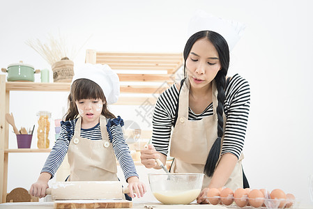 亚洲母亲和女儿正在准备钱 在度假时在厨房做一个蛋糕 来给孩子做蛋糕图片