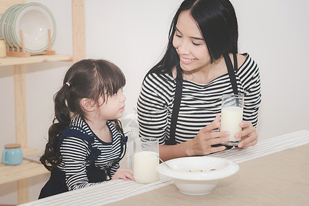 清晨 亚洲母亲的幸福家庭 与她可爱的女儿一起喝牛奶图片