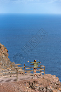 西班牙岛灯塔观察点的金发妇女游客房子蓝色石头风暴冲浪旅游海景小路海岸线图片