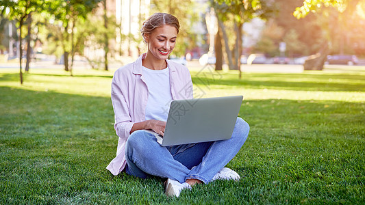 使用笔记本电脑坐在草地夏季公园的女商务人士 商业人员在远距离工作女性草地阳光成功就业生意人学生公园企业家学习图片