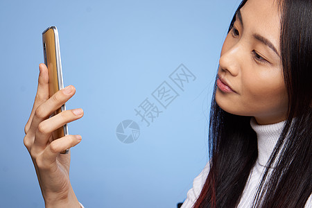 棕色漂亮的黑发美女 手握电话 通讯互联网技术科技蓝背景演播室展示广告女士手机促销商业成人交易乐趣喜悦背景