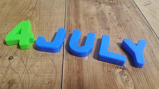 塑料彩色字母表 在木地板上放4July字学习数字学校创造力摄影木板乐趣磁铁静物商业图片