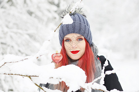美丽的红发女孩装扮成红心挂在雪树枝上图片