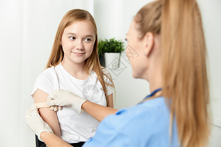 一名女医生在一位女孩旁边用石膏疫苗封住她的手臂图片