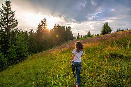 女孩享受纯净的自然 走过田野迎接日落游客裙子栅栏爬坡远足森林活动顶峰成就运动图片