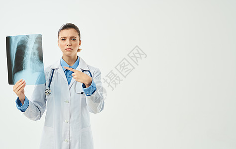 身穿医疗长袍的医生 带着X光照片 用手拍着探照药品扫描诊所骨骼女性职业卫生医院胸部疾病图片