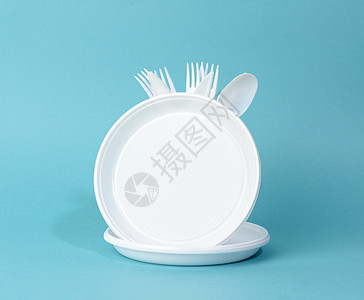蓝色背景的可支配白色塑料餐具板 杯 叉和刀食物盘子勺子刀具圆圈野餐服务用具餐具派对图片