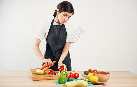 黑围裙剪切蔬菜的女厨师烹饪食品家庭健康食品营养房子围裙桌子微笑沙拉主妇午餐胡椒食物图片