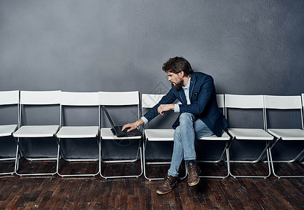 一名穿西装 手持笔记本电脑的男人坐在椅子上等待工作面试就业男性候选人工人会议人士招聘沉思正装经理图片