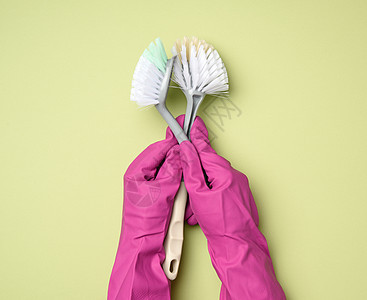 穿紫色橡皮手套的女性手持绿色背景的塑料清洁刷子乳胶乐器手臂消毒安全卫生清洁工红色工具家庭图片