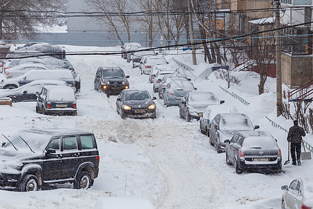 两辆汽车在俄罗斯图拉Tula深雪中的停泊车厢之间穿过一个雪地院子状况影响力天气运输街道测量雪堆车辆公寓社论图片