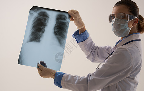 一名戴医疗面具的女医生在轻光背景下检查X光片x射线工作药品保健卫生胸部放射科办公室疾病职业图片