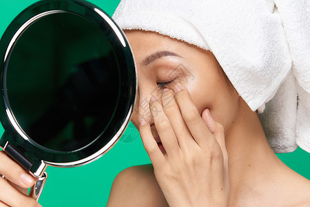 漂亮女人的手照镜子 干净的皮肤 面部紧贴绿色背景毛巾化妆品女士卫生喜悦成人浴室温泉美容师身体图片