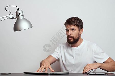 一个男人坐在技术经理通讯灯的工作台旁图片