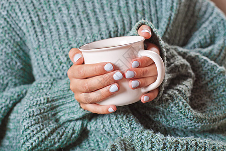 女性握着热咖啡或茶杯的手陶瓷美甲早餐毛衣女士咖啡饮料杯子季节制品图片