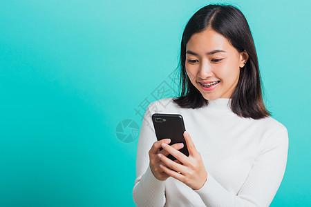 妇女微笑 她拿着并打短信网络社会阅读女孩细胞短信女性技术手机互联网图片