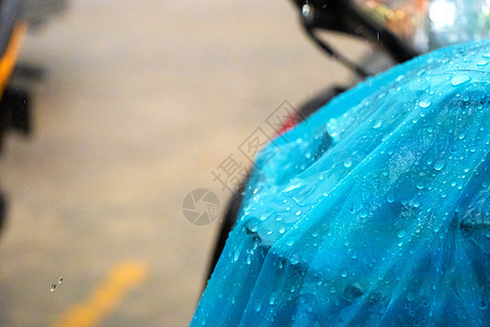 雨中蓝色雨衣上的雨滴被扔到滑板车上的特写摩托车人群天气塑料摩托雨披倾盆大雨下雨行人运输图片