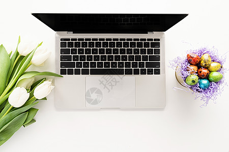 妇女工作空间模拟膝上型计算机 白色郁金香花和在桶中的东蛋图片
