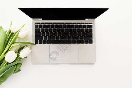 妇女工作空间模拟膝上型计算机和白色郁金花图片
