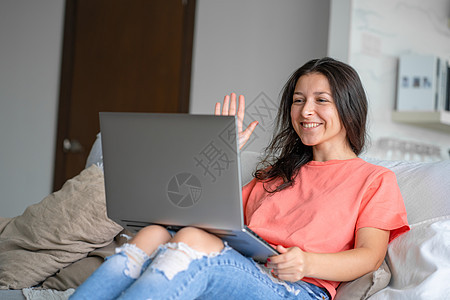 女孩用笔记本电脑躺在沙发上 视频通信 远程工作员 自由职业者 在家工作闲暇微笑女士相机情感教育快乐幸福乐趣互联网图片