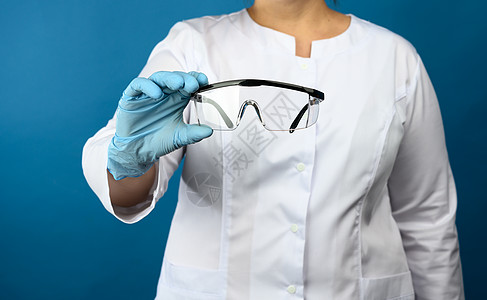 药品ps素材穿着白色医疗长袍的女医生站在蓝色背景上 佩戴保护性塑料眼镜(PS)背景