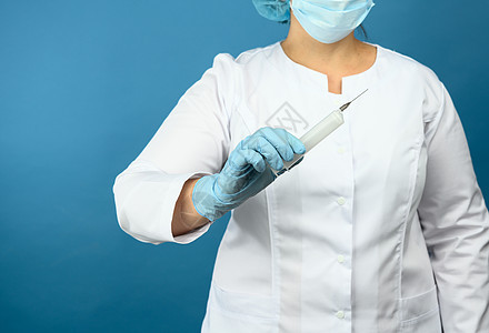 穿白色医疗大衣和戴面罩的医生站在蓝色背景上 并持有塑料注射针筒 疫苗接种概念疾病药物工作治疗抗生素面具医师液体女士女性图片
