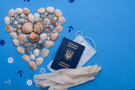 蓝色背景上的心形贝壳 检疫期间的旅行和娱乐 乌克兰医用手套的医用面具生物识别护照 你图片