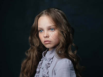 一个穿着灰色裙子的漂亮女孩的肖像 黑暗背景和卷发蓝眼睛沙龙头发微笑女性女孩喜悦皮肤孩子童年魅力图片