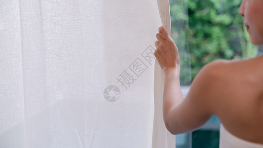 女人手打开白色窗帘窗外绿色花园景观图片