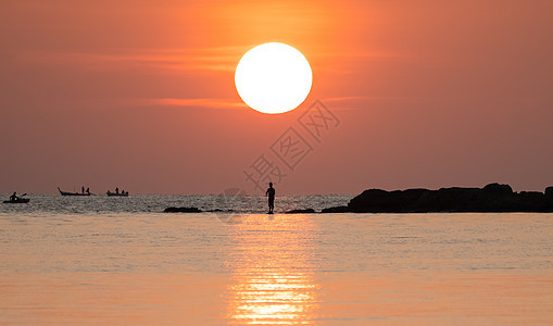 海景日落 橙色天空上海面的太阳 岩石上有钓鱼棒的渔夫日出钓竿反射橙子海洋场景海岸假期海浪海滩图片