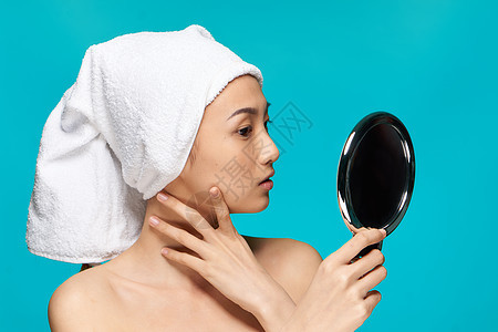 露着肩膀的亚洲女性外貌 头部蓝底脸色照镜子 头上有毛巾身体绿色微笑打扫治疗卫生温泉皮肤美容师背景图片