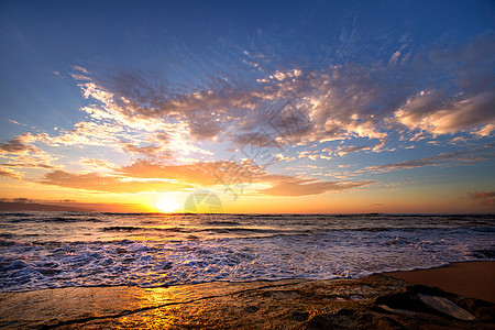 在夏威夷奥胡的日落海滩附近的岩石上 爆发波浪图片