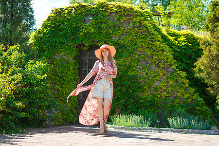 穿着淡夏日服的迷人女孩和佩雷奥帽正在绿色公园行走 享受阳光明媚的暑假裙子喜悦微笑闲暇太阳情感花园幸福帽子女士图片