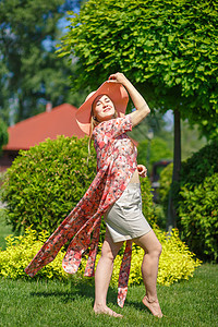 穿着淡夏日服的迷人女孩和佩雷奥帽正在绿色公园行走 享受阳光明媚的暑假裙子情感自由晴天花园太阳女性女士喜悦魅力图片