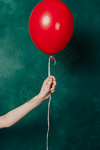 绿背景近身女手的充气红气球 绿色背景特写笑声女士奢华红灯成人工作室裙子乐趣魅力头发图片