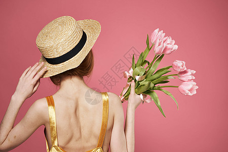 女人戴帽子后背看花束 作为礼物粉红背景图片