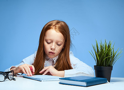 红头发女孩坐在有教科书教学课程学校培训的桌边上童年学习青少年家庭作业婴儿课堂绘画教育女学生思维图片