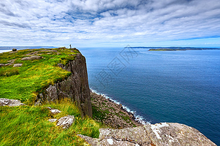 乘客背背包站在悬崖边的旅游者 Fair Head 北爱尔兰 英国旅行女士全景顶峰悬崖女性冒险县城旅游闲暇背景图片