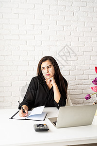 一位年轻的女商务人士花店在笔记本上写字 在办公室使用笔记本电脑药片桌子自由职业者技术房间职场郁金香女性花朵职业图片