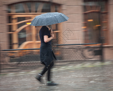 雨天人们在街上走着女士运动场景水坑人行道风暴街道冷藏生活路面图片