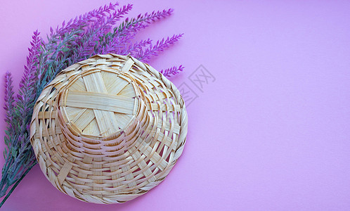 一个帽子形状的篮子躺在粉红色背景的人造薰衣草树枝上  tex 的空间图片